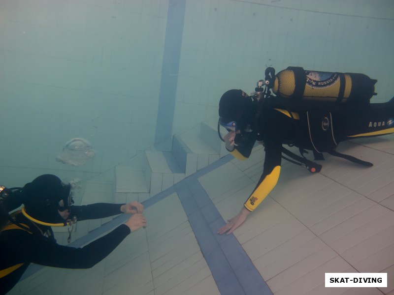 Черникова Ольга, при поддержке инструктора и под постоянным его контролем самостоятельно спускается на глубокую часть бассейна