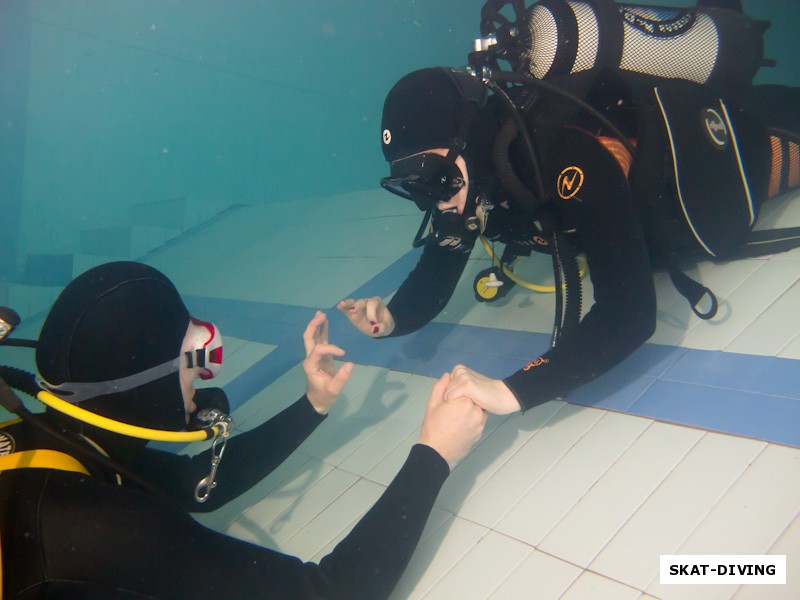 Алешина Елена, медленно, под постоянным контролем инструктора, погружается на глубокую часть бассейна