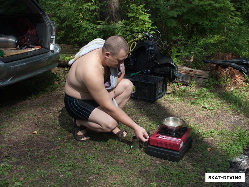 Быченков Дмитрий, подогревает воду для час на газовой горелке