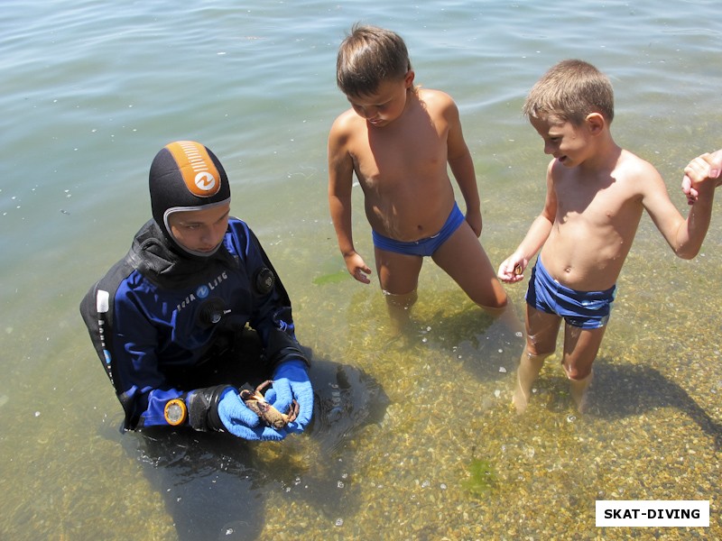 Зеленев Максим, аккуратно демонстрирует детишкам на пляже свою находку: каменного краба